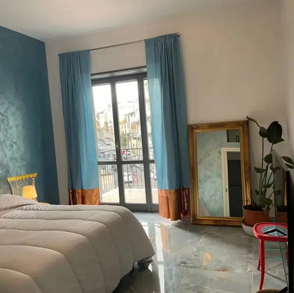 Camera del bilocale Natura con porta finestra sul balcone e specchio dorato